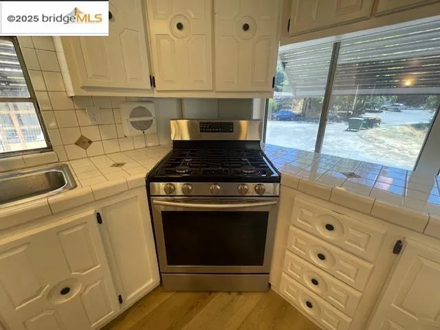 a kitchen with granite countertop white cabinets and a stove