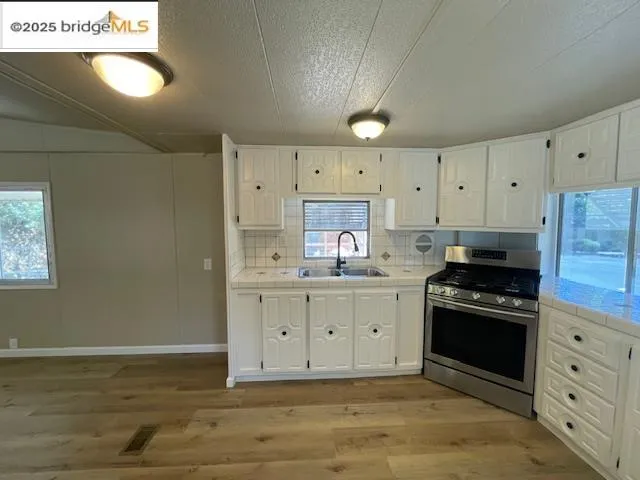 a kitchen with granite countertop white cabinets and stainless steel appliances