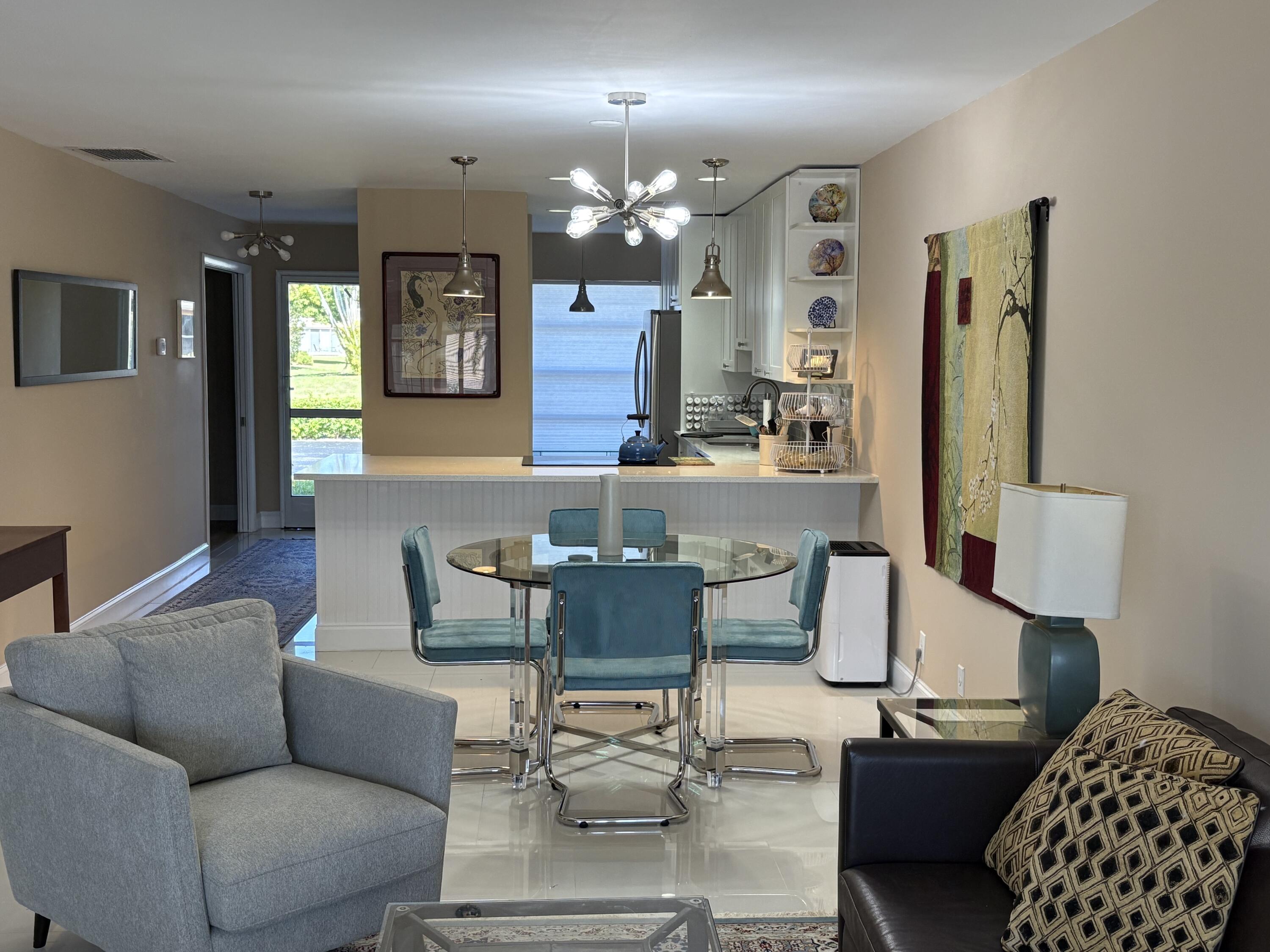 1680 Northwest 20th Avenue, Unit 102 Delray Beach, FL 33445 - Photo 7 of 17 a living room with furniture and a chandelier