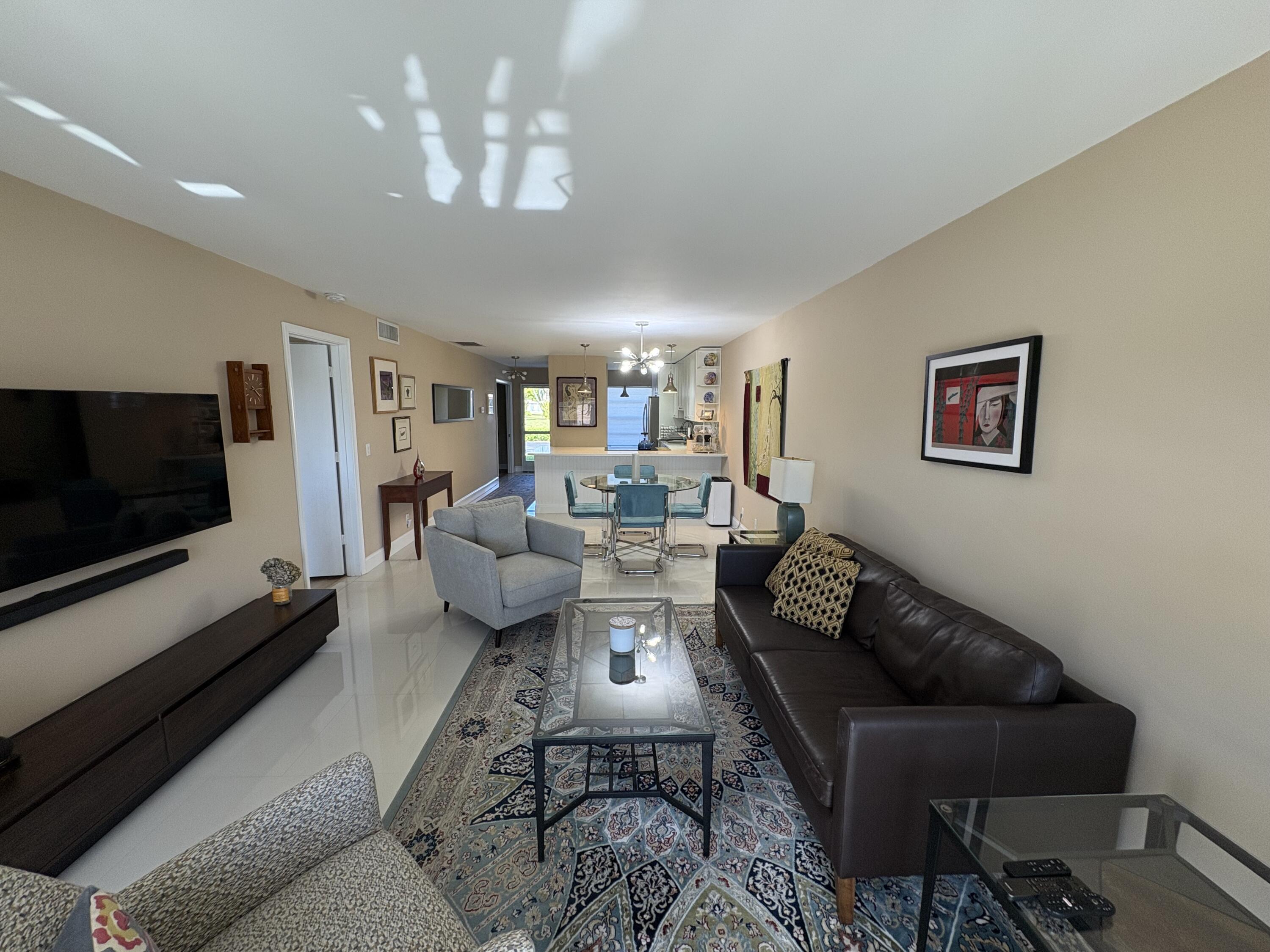 1680 Northwest 20th Avenue, Unit 102 Delray Beach, FL 33445 - Photo 8 of 17 a living room with furniture and a flat screen tv