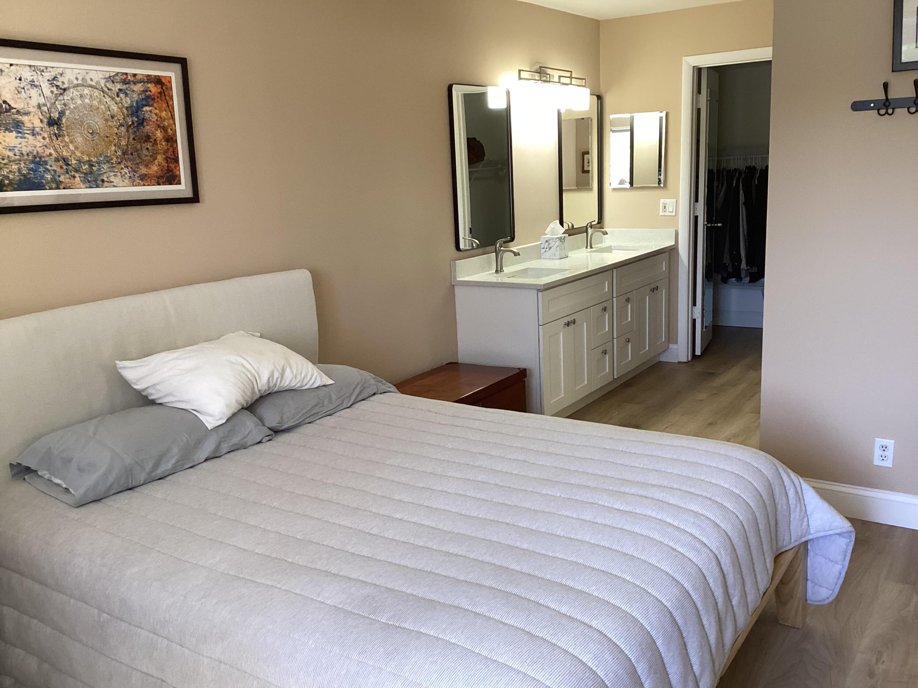 1680 Northwest 20th Avenue, Unit 102 Delray Beach, FL 33445 - Photo 9 of 17 a bedroom with a bed and a large mirror