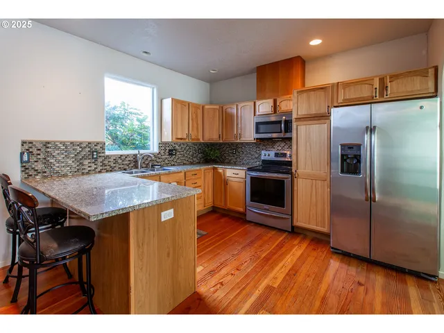 a kitchen with kitchen island granite countertop wooden floors and stainless steel appliances