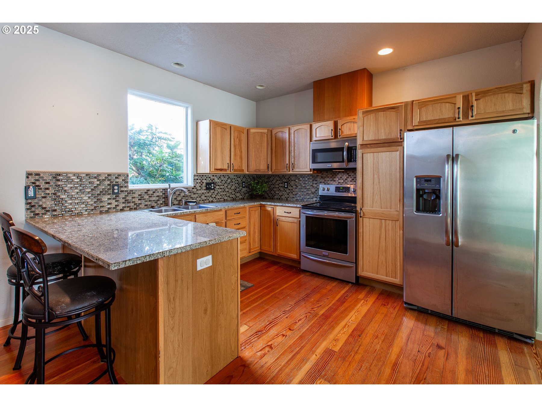 6964 Bluebelle Way Springfield, OR 97478 - Photo 8 of 35 a kitchen with kitchen island granite countertop wooden floors and stainless steel appliances
