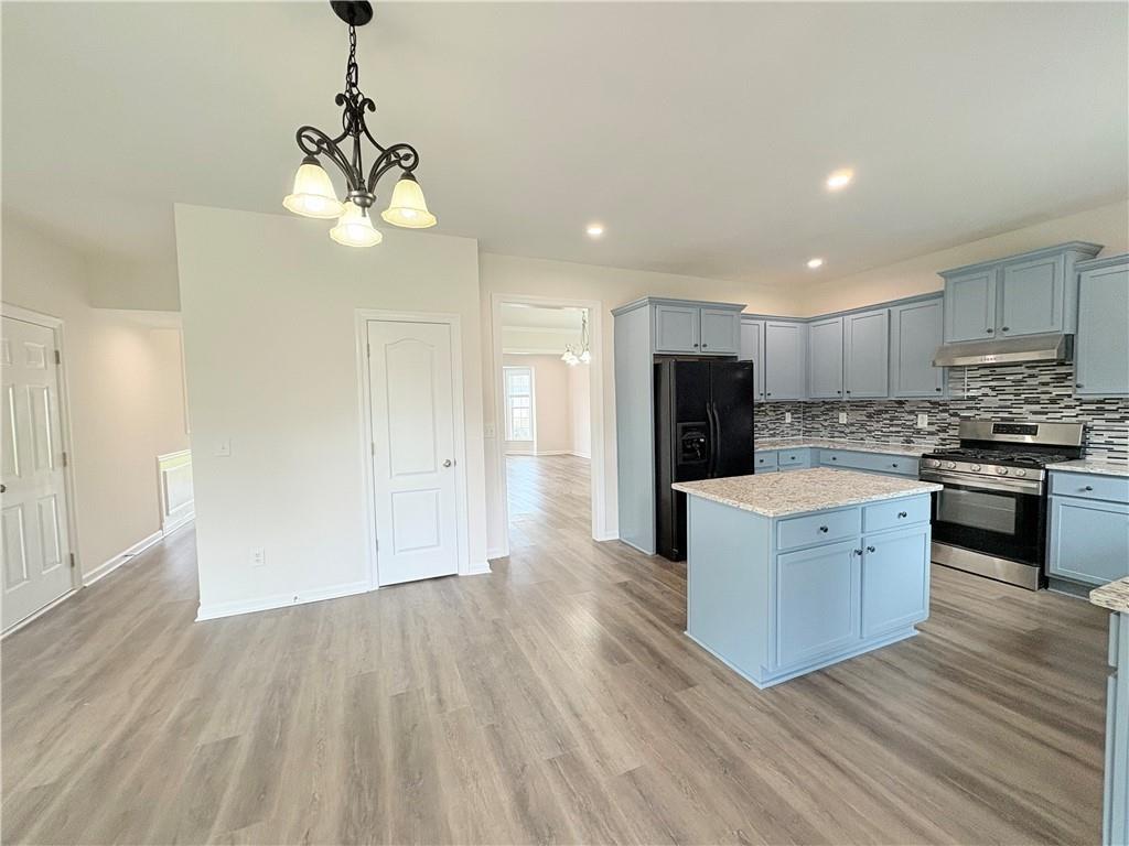 4195 Settlers Grove Road Cumming, GA 30028 - Photo 7 of 38 a large kitchen with stainless steel appliances granite countertop a refrigerator a sink dishwasher a stove and white cabinets with wooden floor