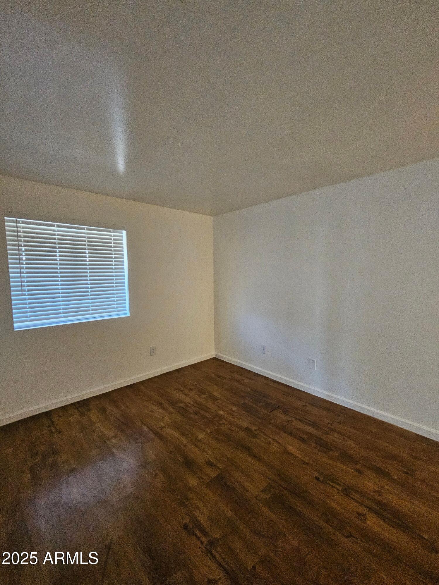 180 North Apache Road, Unit 24 Buckeye, AZ 85326 - Photo 11 of 32 a view of an empty room with wooden floor and a window