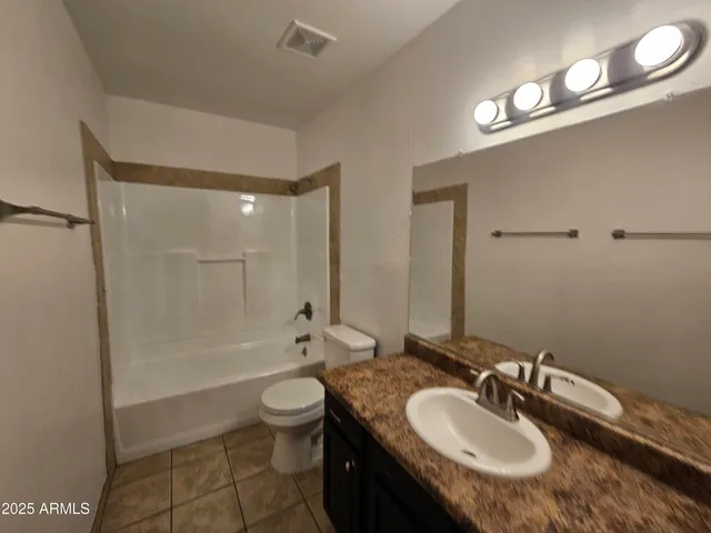 a bathroom with a granite countertop sink a toilet a mirror and shower