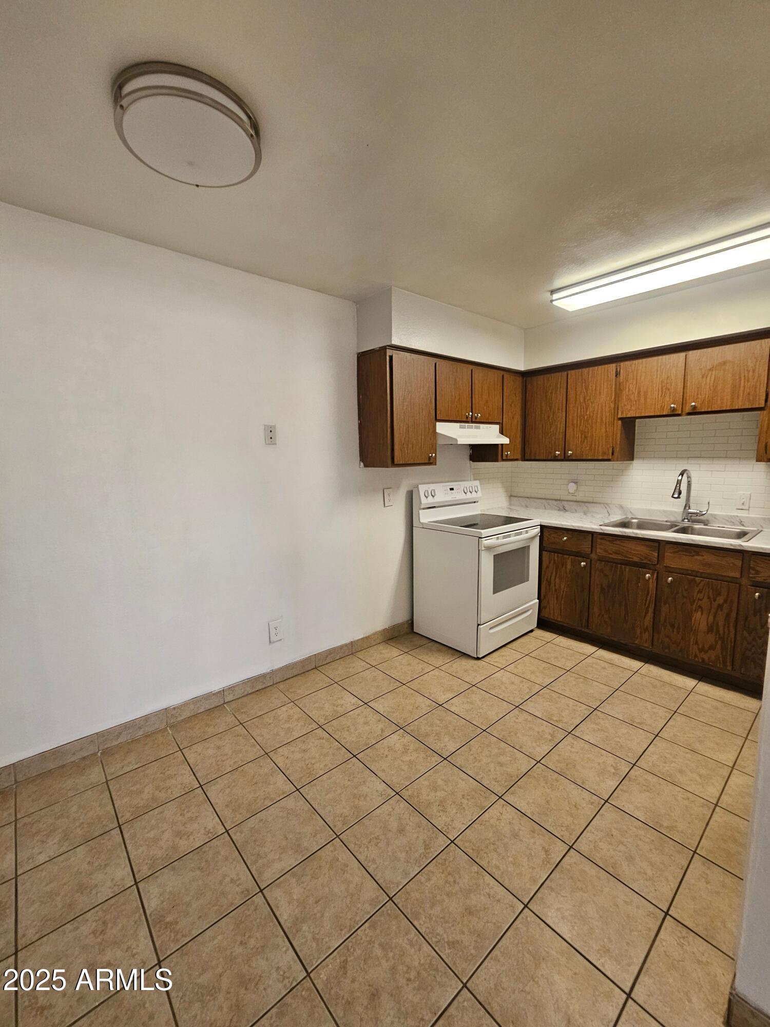 180 North Apache Road, Unit 24 Buckeye, AZ 85326 - Photo 17 of 32 a kitchen with a sink a stove and cabinets