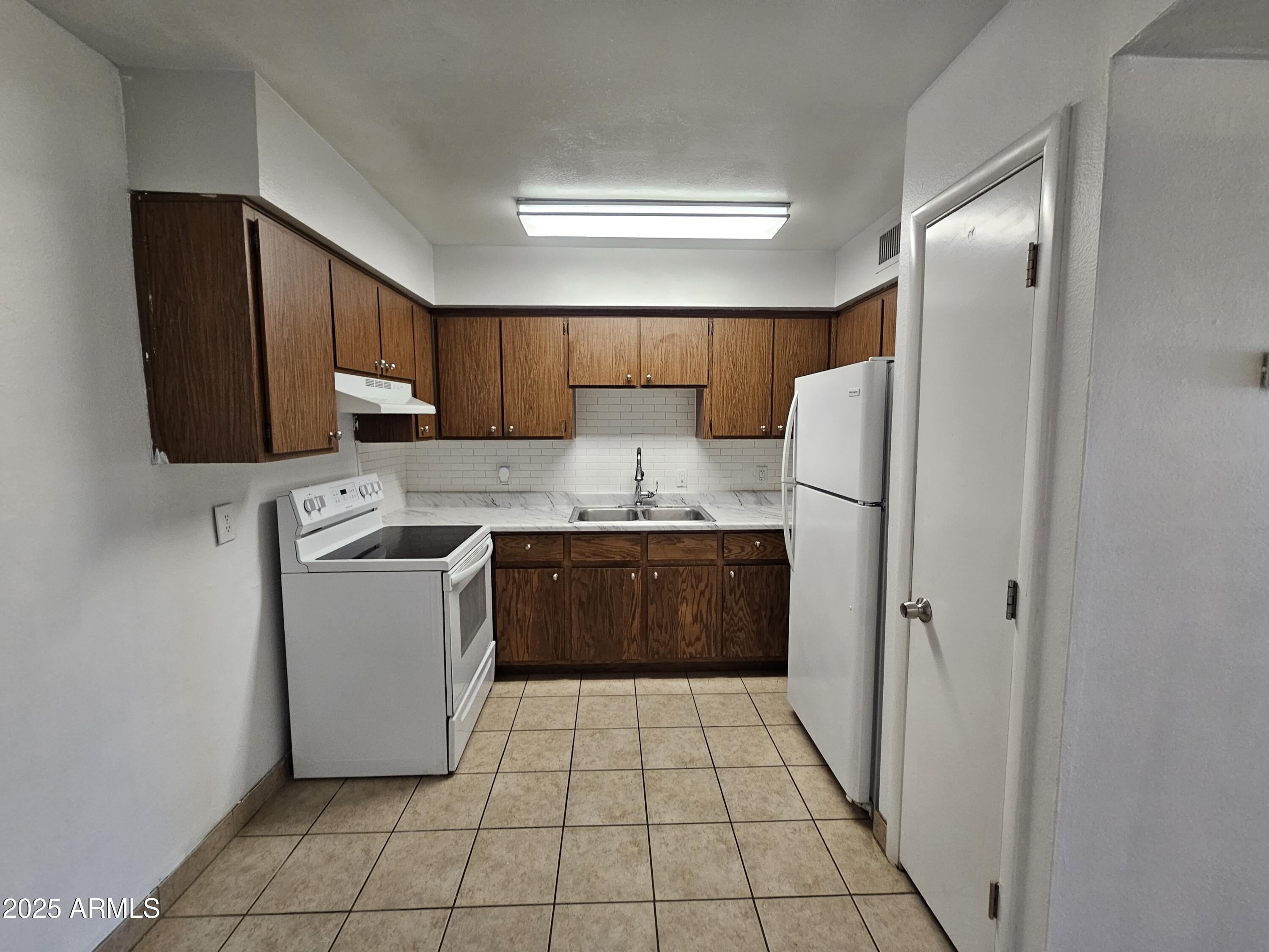 180 North Apache Road, Unit 24 Buckeye, AZ 85326 - Photo 19 of 32 a kitchen with stainless steel appliances granite countertop a refrigerator stove a sink and a microwave oven