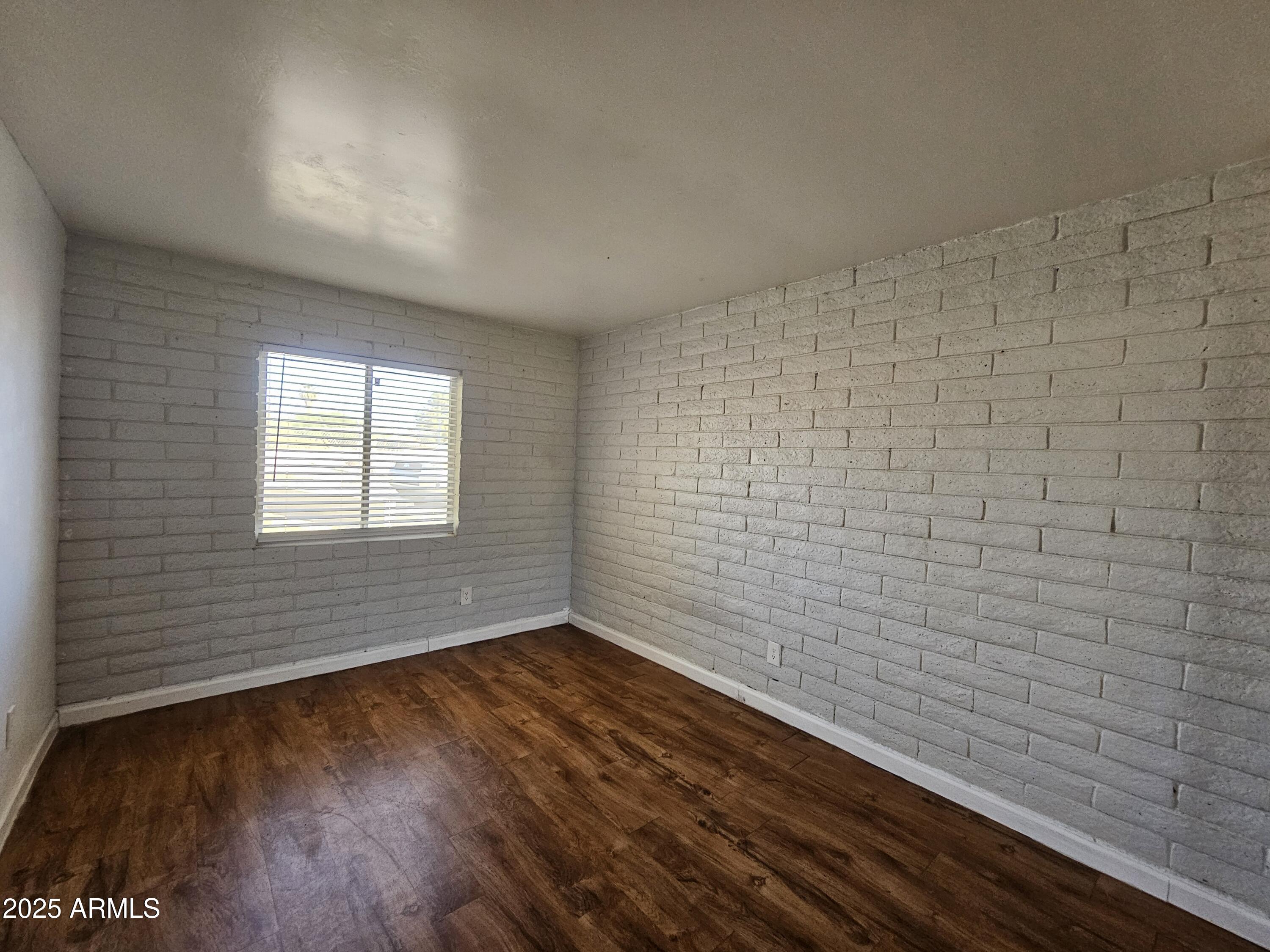 180 North Apache Road, Unit 24 Buckeye, AZ 85326 - Photo 27 of 32 a view of an empty room with wooden floor and a window