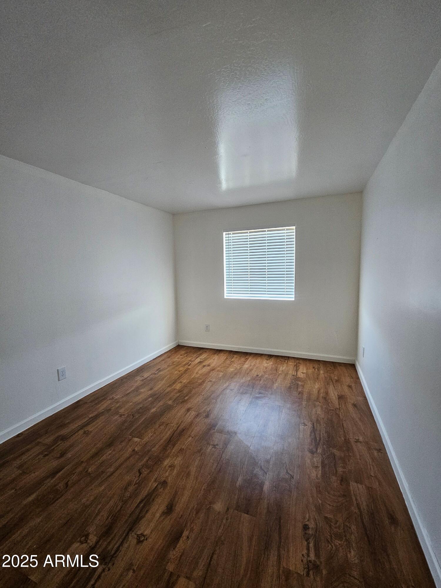 180 North Apache Road, Unit 24 Buckeye, AZ 85326 - Photo 5 of 32 an empty room with wooden floor and windows