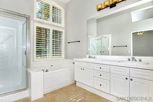 a bathroom with a granite countertop sink mirror bathtub and next to a window