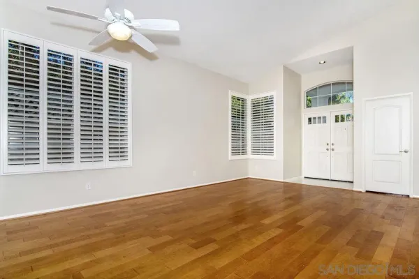 a view of an empty room with a window and wooden floor