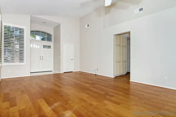 a view of an empty room with wooden floor and a window