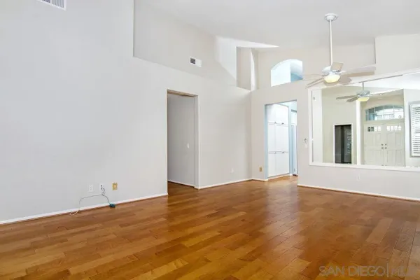 a view of an empty room with chandelier and wooden floor