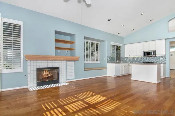 a view of an empty room with kitchen and a window