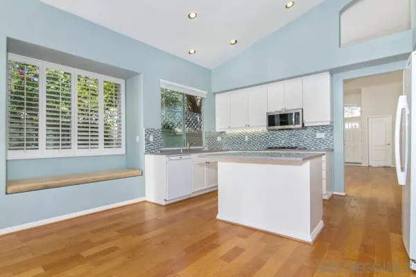 a large kitchen with kitchen island granite countertop a stove a sink and a granite counter tops with white cabinets