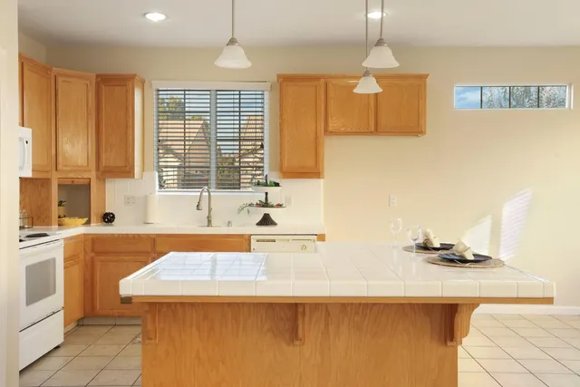 a view of a kitchen with kitchen island granite countertop a sink cabinets and window