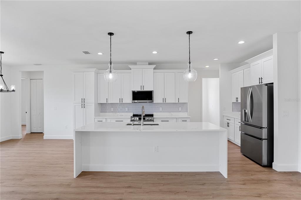 2805 Anniston Road North Port, FL 34288 - Photo 6 of 24 a large kitchen with stainless steel appliances kitchen island a large counter top and wooden floors