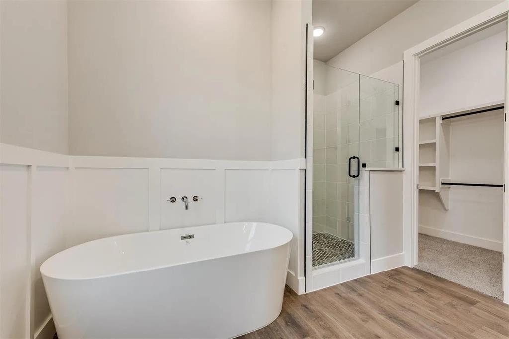 1327 Selby Road Van Alstyne, TX 75495 - Photo 26 of 32 Full bathroom with a stall shower, a spacious closet, wood finished floors, a freestanding bath, and a decorative wall