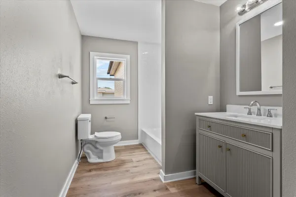 a bathroom with a granite countertop toilet a sink and a mirror