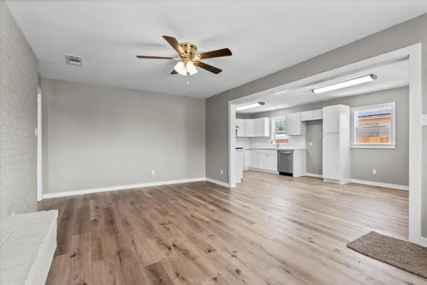 a view of an empty room with a window and wooden floor
