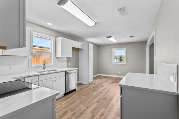 a kitchen with granite countertop a sink stainless steel appliances and window