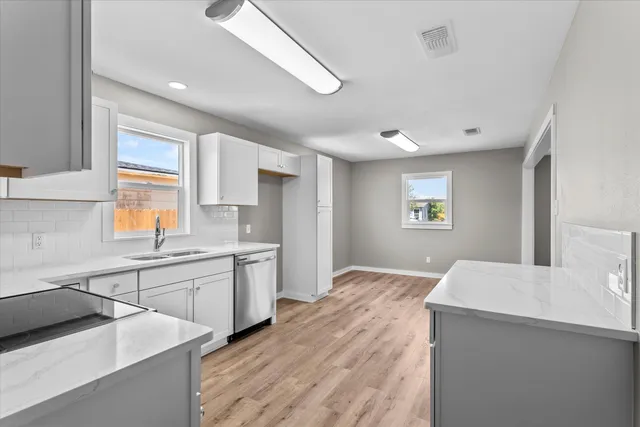 a kitchen with granite countertop a sink stainless steel appliances and window