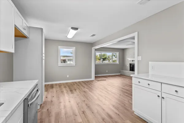 a view of a kitchen with wooden floor electronic appliances and windows