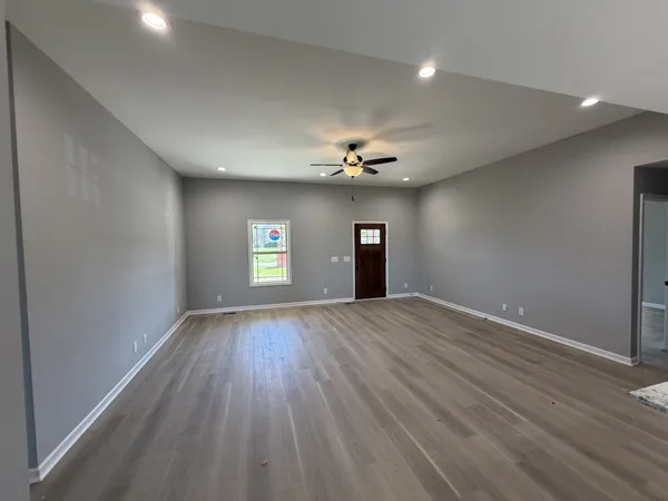 a view of an empty room with wooden floor and window