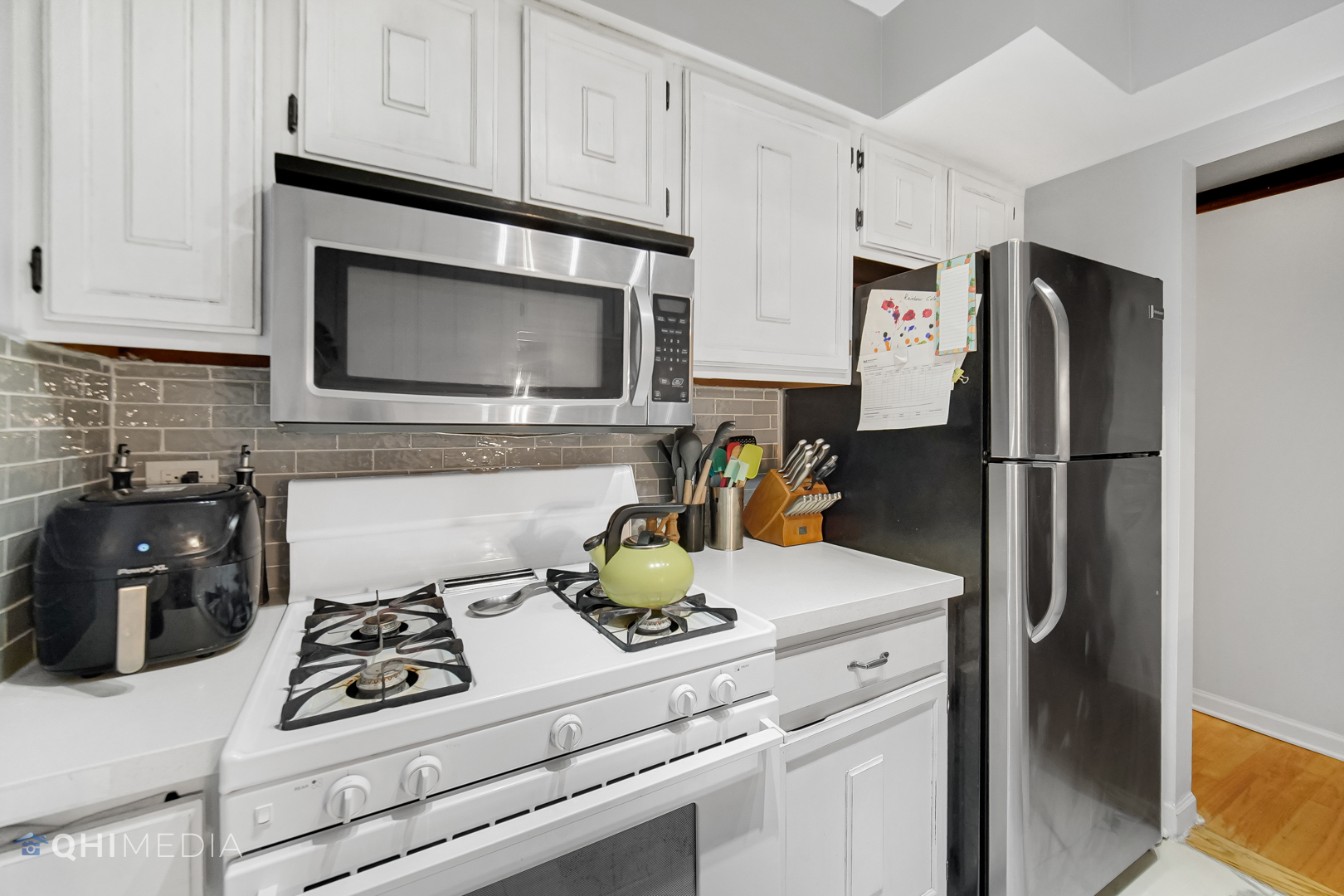 484 Timber Ridge Drive, Unit 106 Carol Stream, IL 60188 - Photo 8 of 23 a kitchen with refrigerator a stove a microwave and cabinets