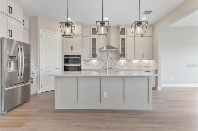 a view of an empty room with wooden floor and a ceiling fan
