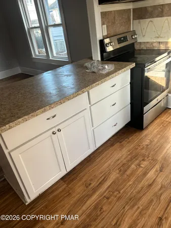 a kitchen with granite countertop white cabinets and a wooden floor