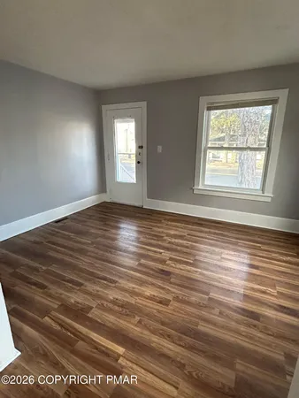 a view of an empty room with wooden floor and a window