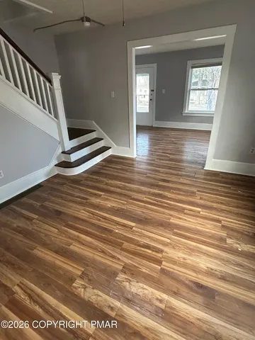 a view of an empty room with wooden floor and a window