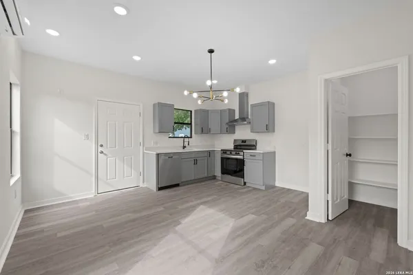 a large white kitchen with a stove top oven and chandelier