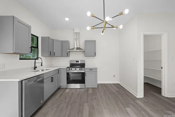 a kitchen with stainless steel appliances a sink cabinets and wooden floor