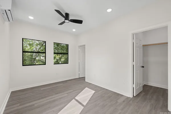 a view of an empty room with wooden floor and a window