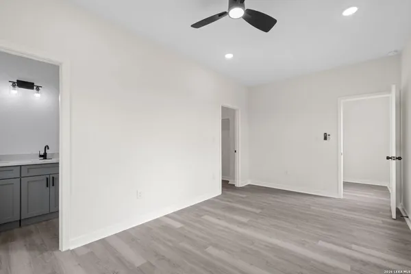 an empty room with wooden floor and fan