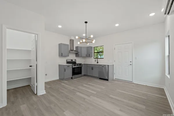 a large white kitchen with a refrigerator a stove a sink dishwasher a dining table and chairs with wooden floor