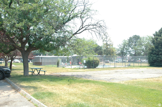 46 Lester Avenue, Unit G 24 Murray, UT 84107 - Photo 5 of 16 Recreational area featuring a fenced swimming pool, surrounding green space, mature trees, and a picnic table