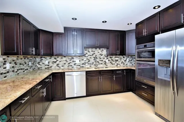 a kitchen with stainless steel appliances granite countertop a stove refrigerator and cabinets