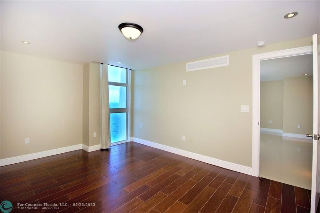 1360 South Ocean Boulevard, Unit 2806 Pompano Beach, FL 33062 - Photo 16 of 37 an empty room with wooden floor and windows