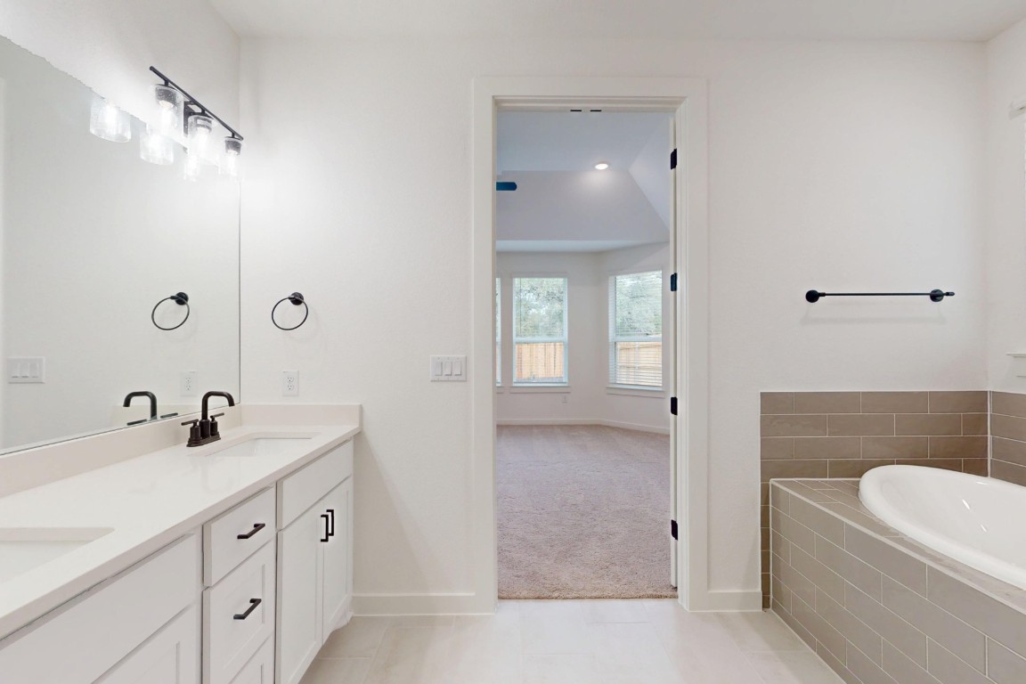 3913 Waxahachie Road Leander, TX 78641 - Photo 31 of 39 a bathroom with a tub a sink and mirrors