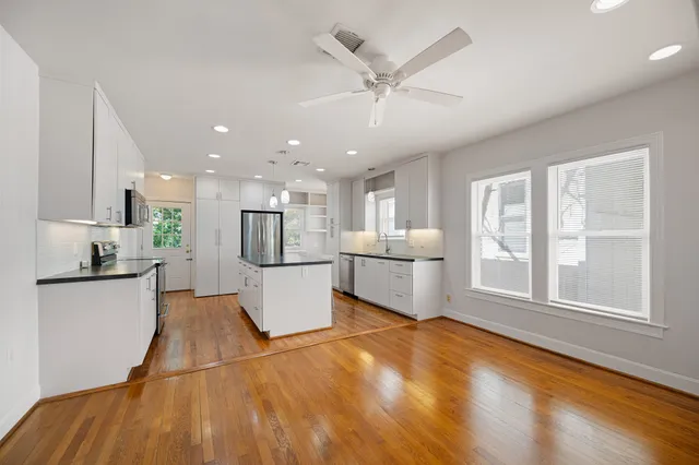 a large white kitchen with white cabinets and wooden floor