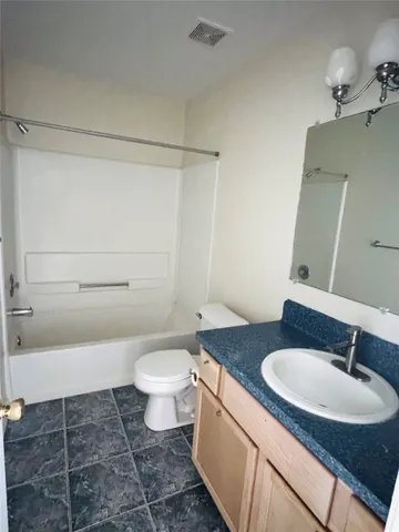 a bathroom with a granite countertop sink toilet a mirror and shower