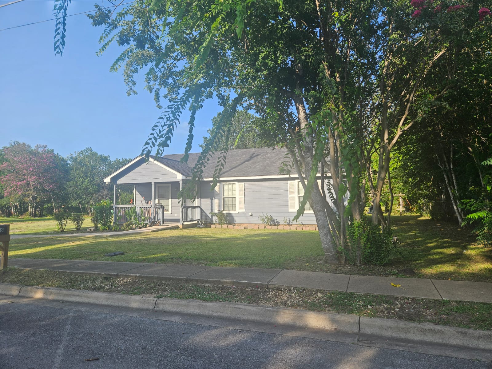 606 Trinity Street Lockhart, TX 78644 - Photo 3 of 23 A charming residence with a covered front porch, nestled amidst mature trees.