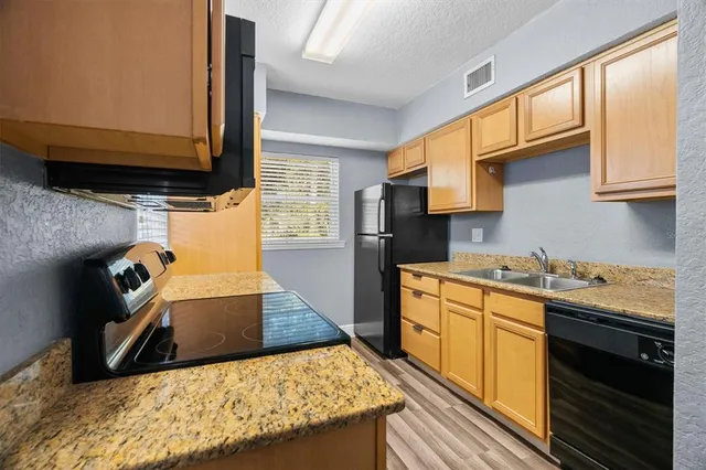 a kitchen with granite countertop stainless steel appliances window a sink and cabinets