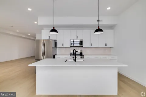 a kitchen with kitchen island a white counter top space cabinets and stainless steel appliances