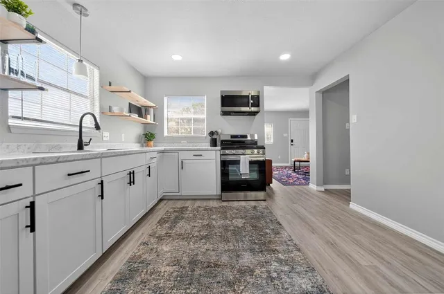 a kitchen with stainless steel appliances granite countertop a sink a stove and a refrigerator