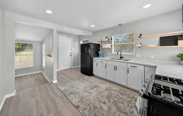 a kitchen with stainless steel appliances a stove top oven a sink dishwasher and a refrigerator